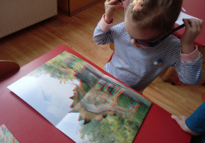 Dziecko ogląda ilustrację dinozaura w okularach 3D